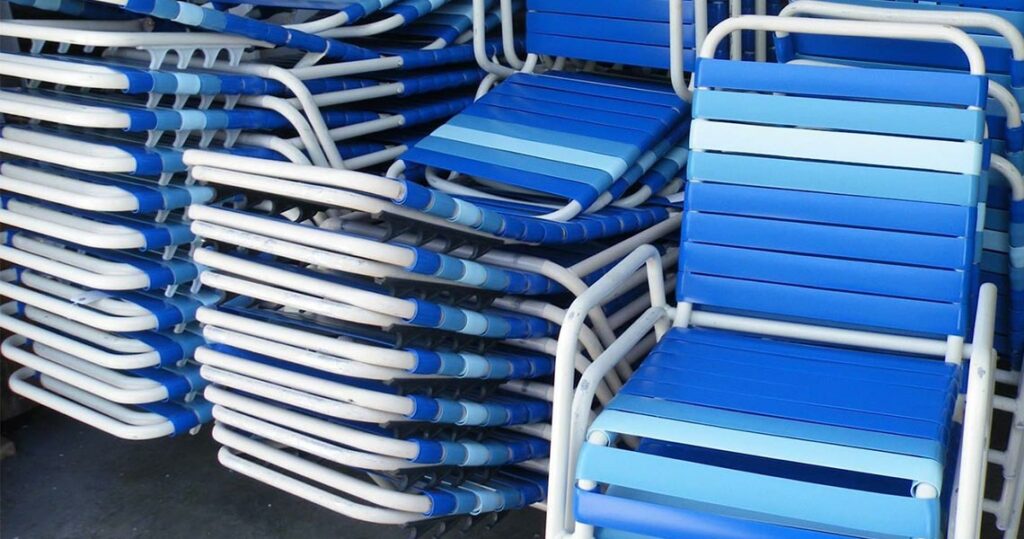 Blue vinyl strapped outdoor chairs stacked on top of each other