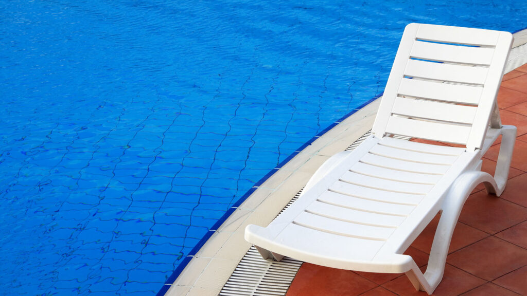 White poolside lounge chair next to an infinity pool